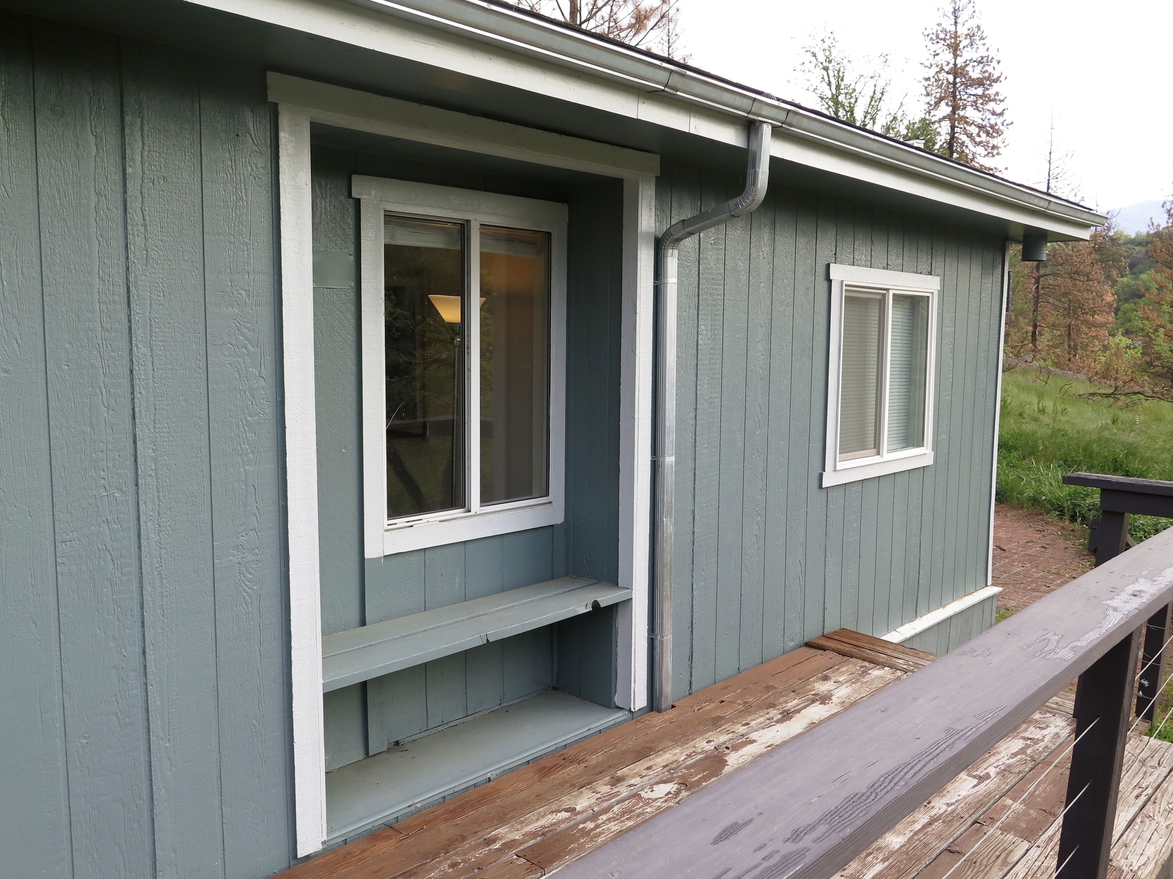 A small, single-story building with a grey exterior and white trim around the windows and door.