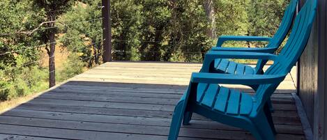 A wooden deck with two blue chairs and a metal railing.