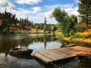 Un lac paisible avec une jetée en bois qui s’avance sur l’eau, entouré d’arbres et sous un ciel dégagé.