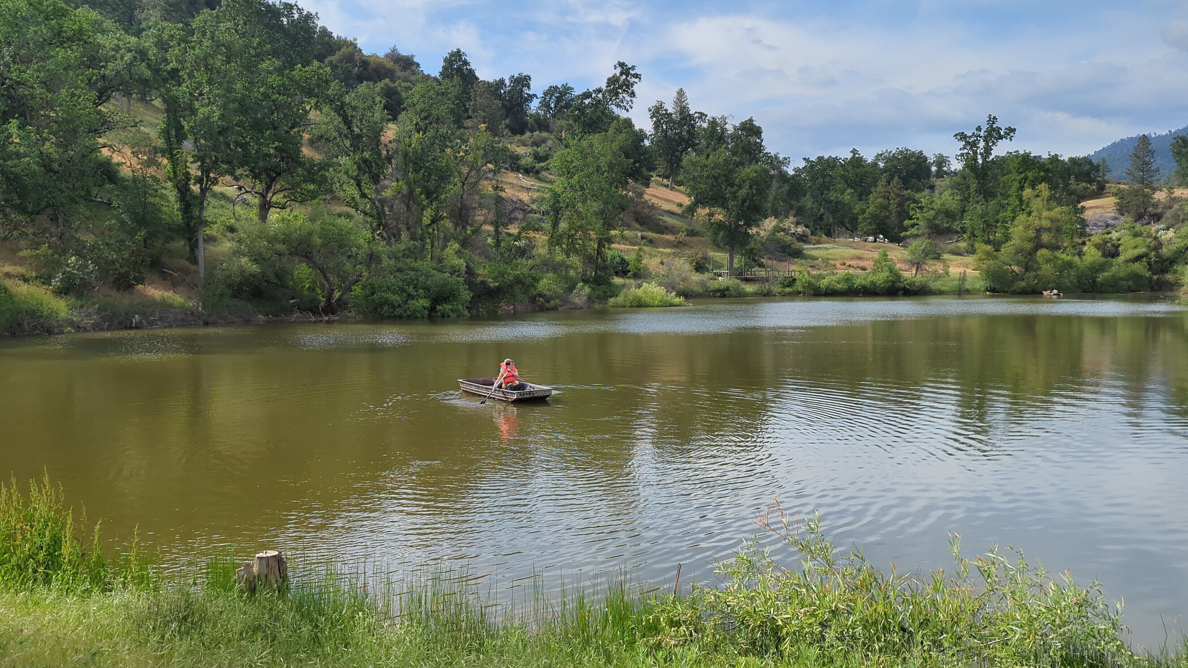 Un río tranquilo con una barca y una persona remando.