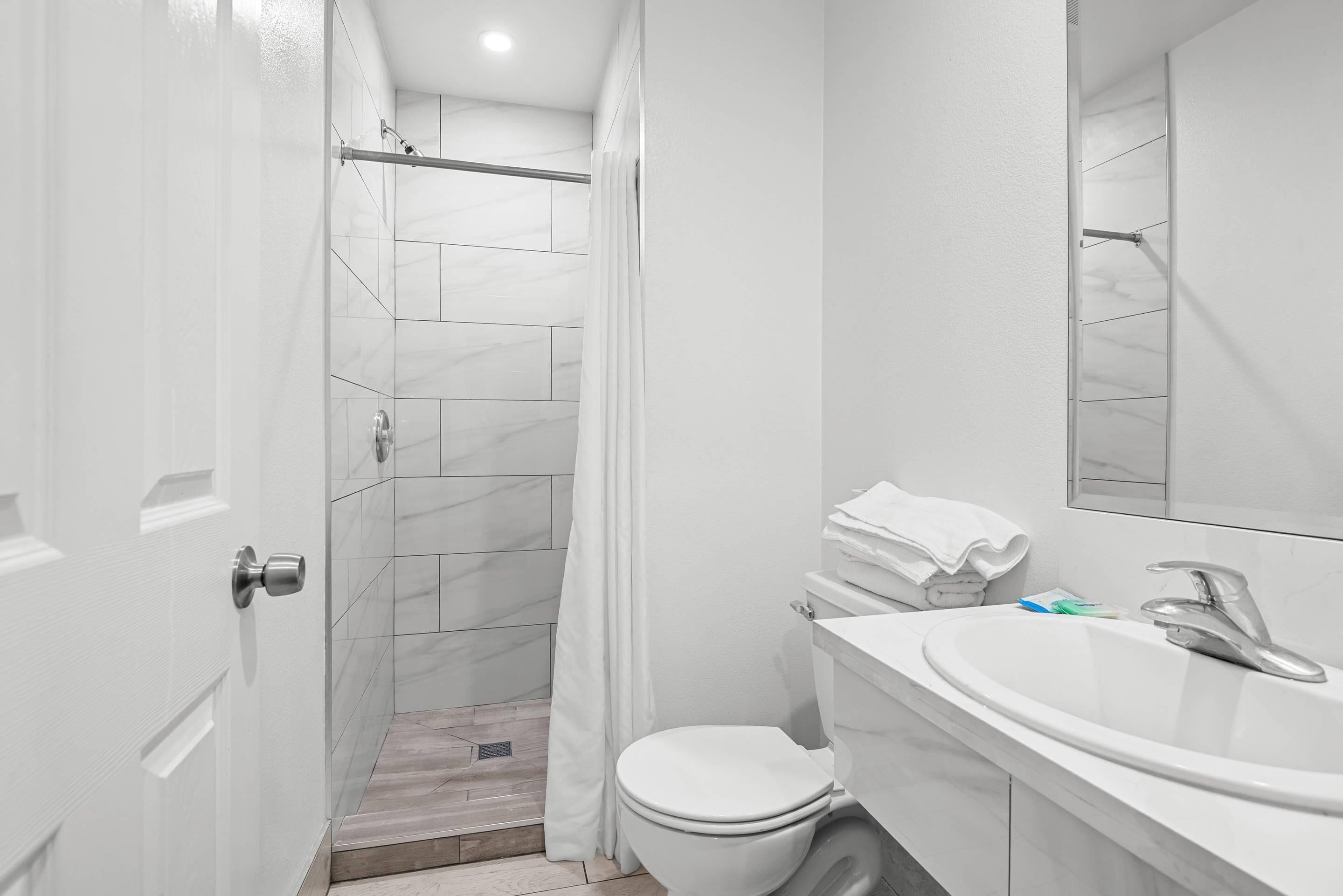 A modern bathroom with a shower, toilet, and sink.