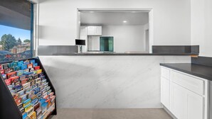 A modern kitchen with white cabinets, a marble countertop, and a view of the city through a window. - Rodeway Inn Commerce - Los Angeles (Los Angeles)