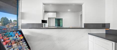 Una cocina moderna con armarios blancos, encimera de mármol y vistas a la ciudad a través de un ventanal.