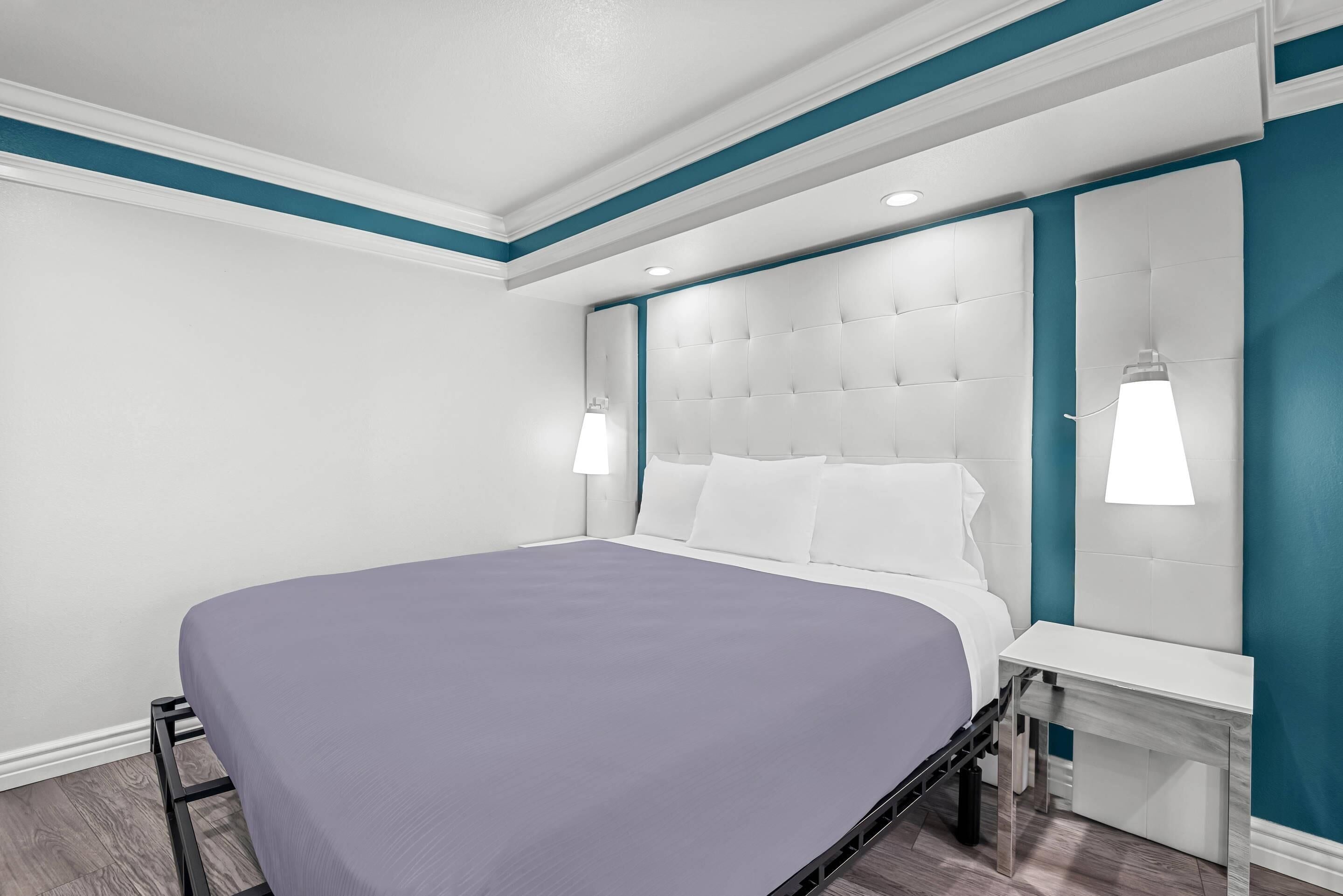 A modern bedroom with a bed, bedside tables, and a headboard with built-in lighting.
