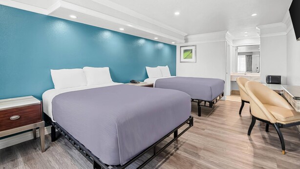 A hotel room with two beds, a desk, a chair, and a TV. - Rodeway Inn Commerce - Los Angeles (Los Angeles)