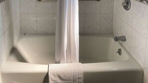 Una vasca da bagno con tenda, un asciugamano e una sbarra di sostegno.