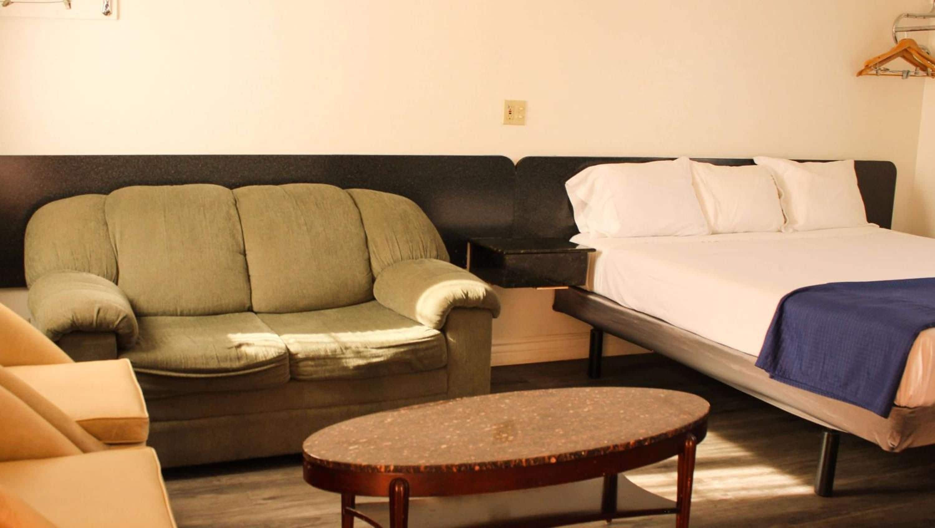 A room with a bed, a sofa, and a small round table.