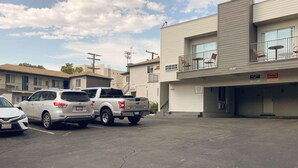 Un parcheggio con due SUV e un'auto bianca. Si nota un edificio con un cartello che indica area di parcheggio riservata ai clienti.