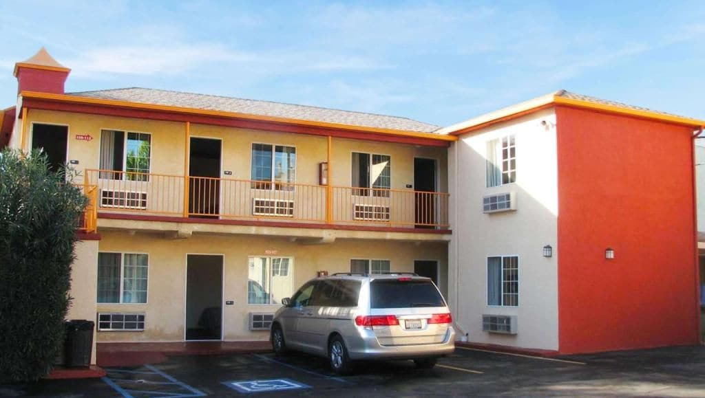 A two-story motel with a parking lot and a single-story building adjacent to it.