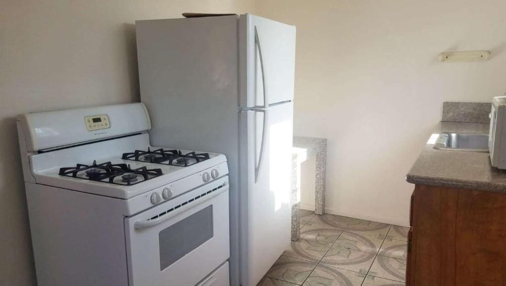 A kitchen with a gas stove, a white refrigerator, and a countertop.