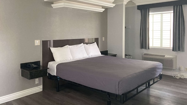 Una camera da letto moderna con un letto grande, un comodino e una finestra con tende.