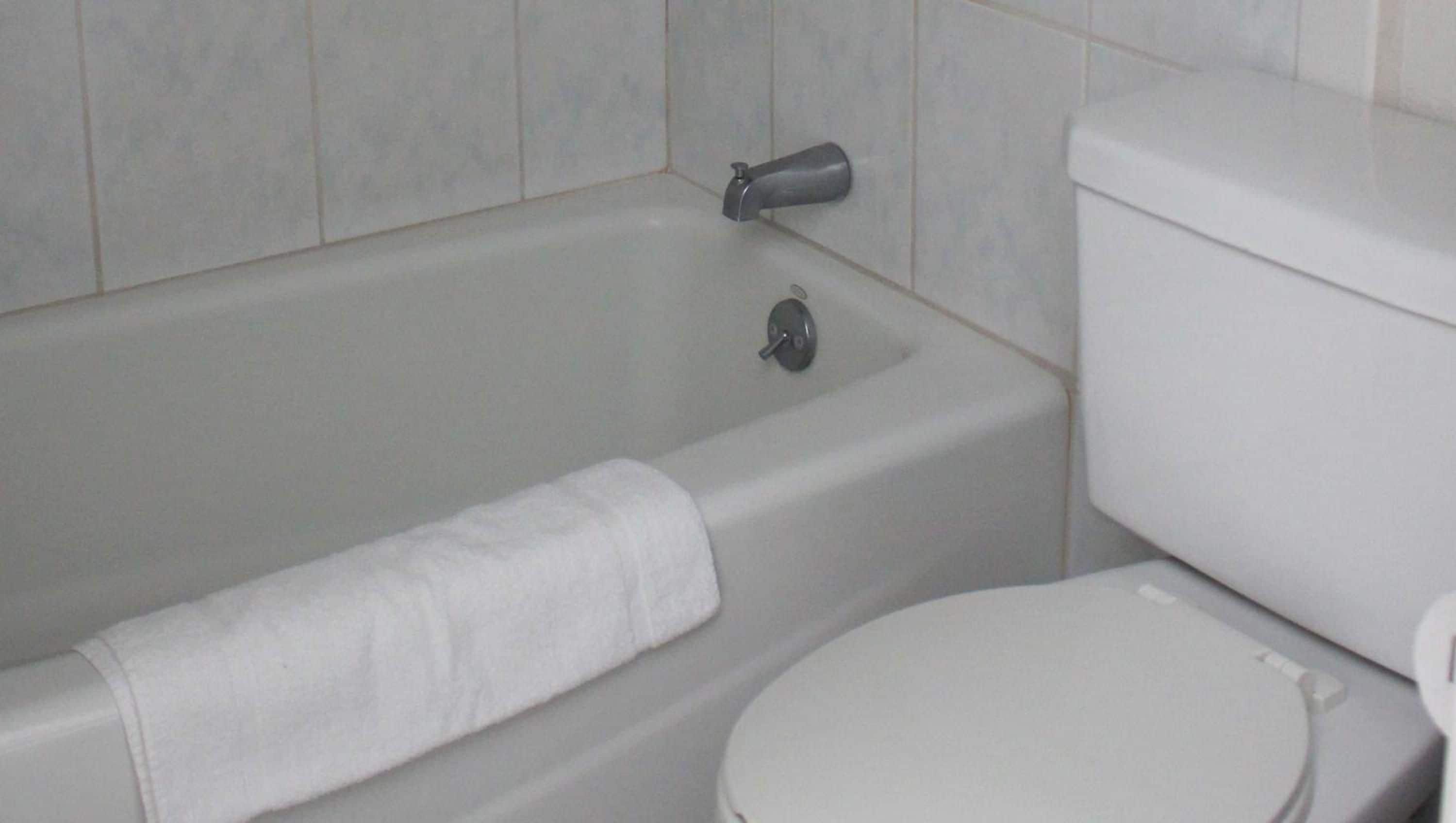 A bathroom with a bathtub, toilet, and a towel.