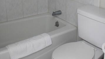 A bathroom with a bathtub, toilet, and a towel.