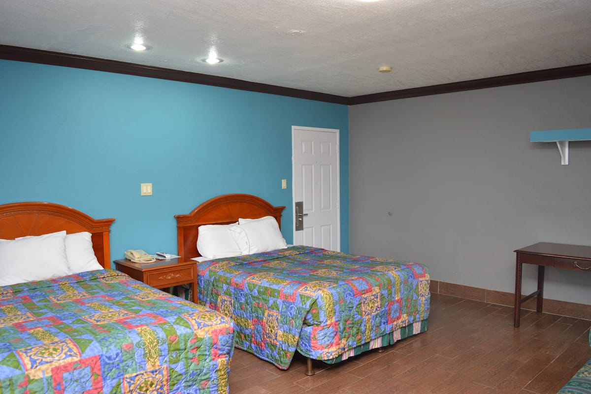 A room with two beds, a desk, and a door.