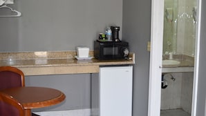 Et kompakt tekøkken med en mikrobølgeovn, et lille køleskab og en kaffemaskine på bordpladen.