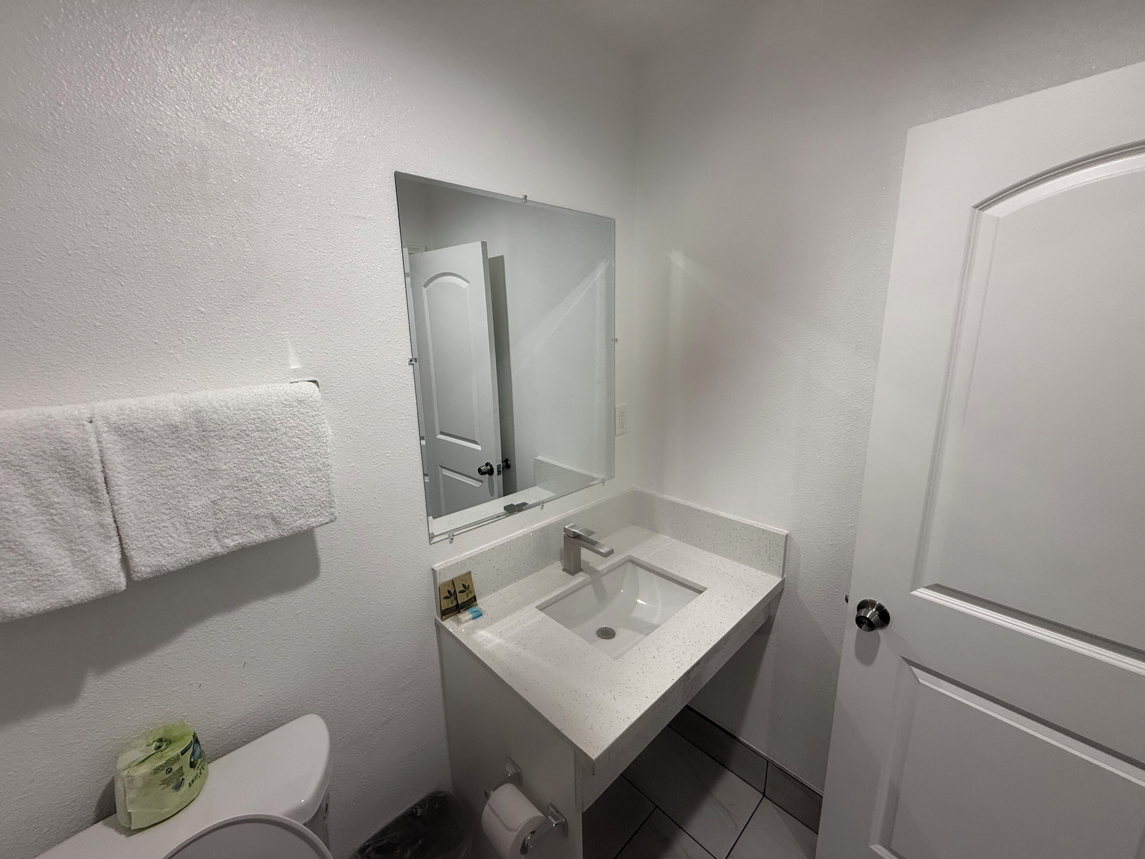 Un baño pequeño y limpio con un lavamanos blanco, un espejo y un inodoro.