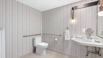 A modern bathroom with striped wallpaper, a toilet, a sink with a mirror, and a towel rack.