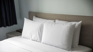 A neatly made bed with white linens and pillows, a wooden headboard, and a nightstand with a lamp. - Ocean Park Hotel (Santa Monica)