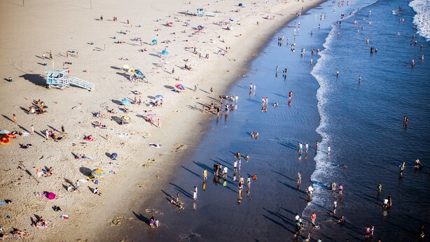 A beach with people sunbathing and swimming. - Ocean Park Hotel (Santa Monica)
