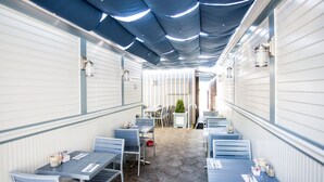 A restaurant with a long, narrow layout, stone flooring, and blue tables and chairs. - Ocean Park Hotel (Santa Monica)