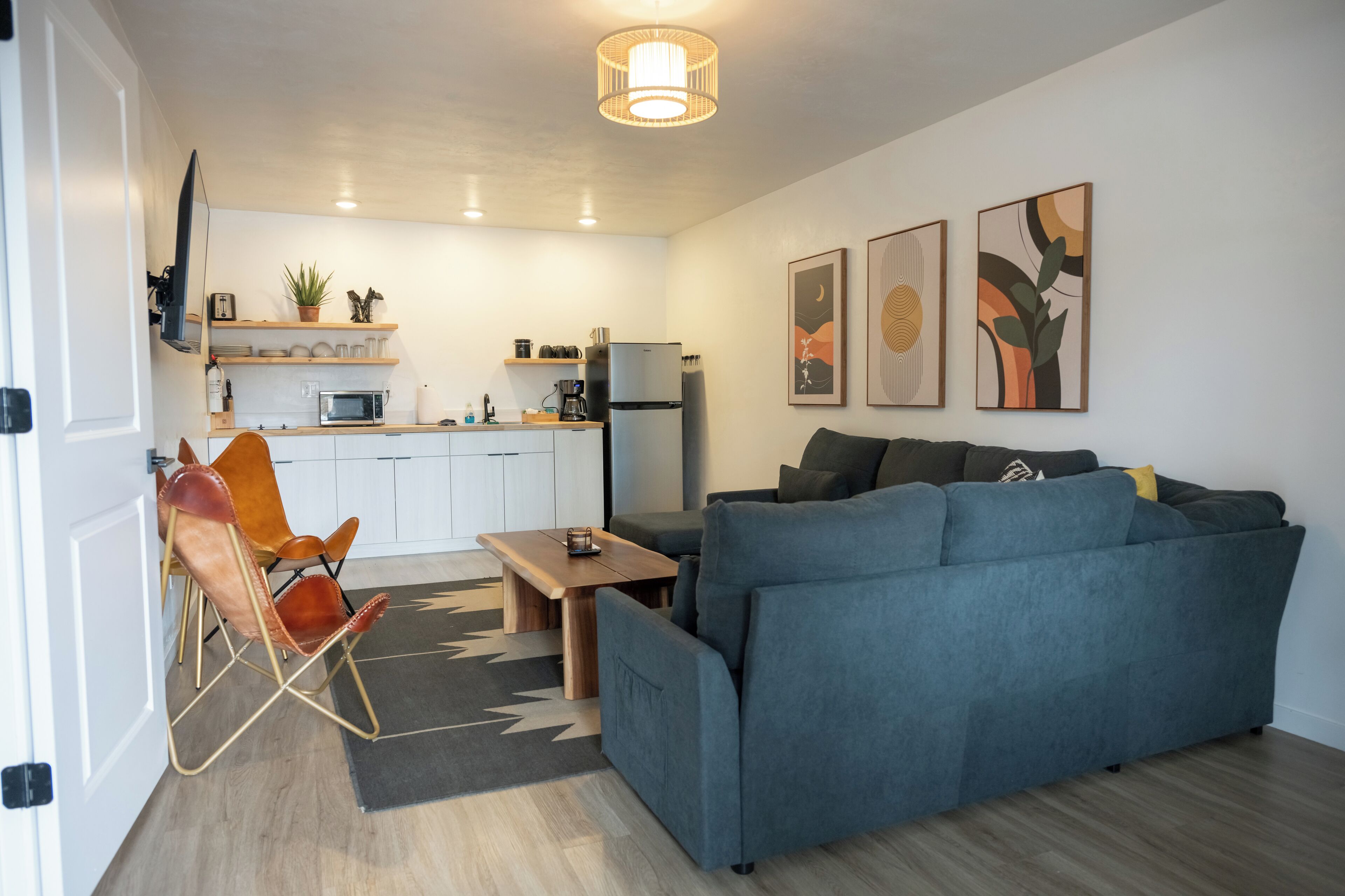 A modern living room with a blue sofa, a wooden coffee table, and a leather chair.