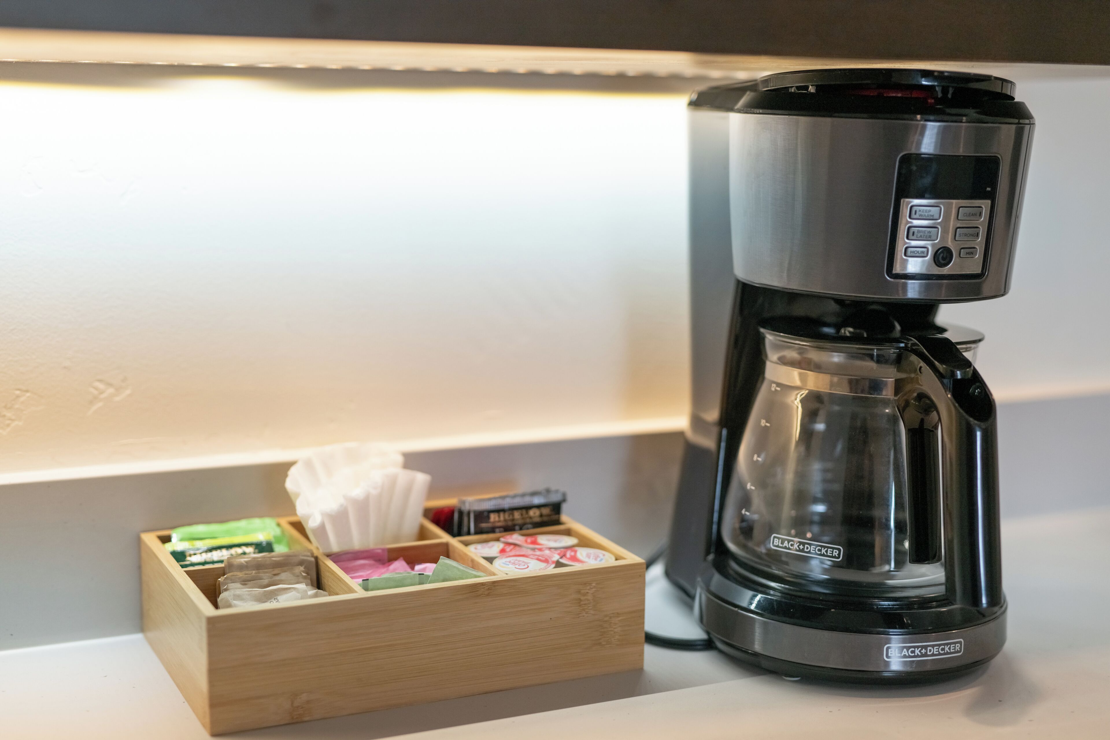 Een koffiezetapparaat met een bedieningspaneel en een houten doosje met koffiekapsules en zakdoekjes.