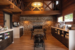 Un comedor rústico con pared de piedra, vigas de madera y chimenea.