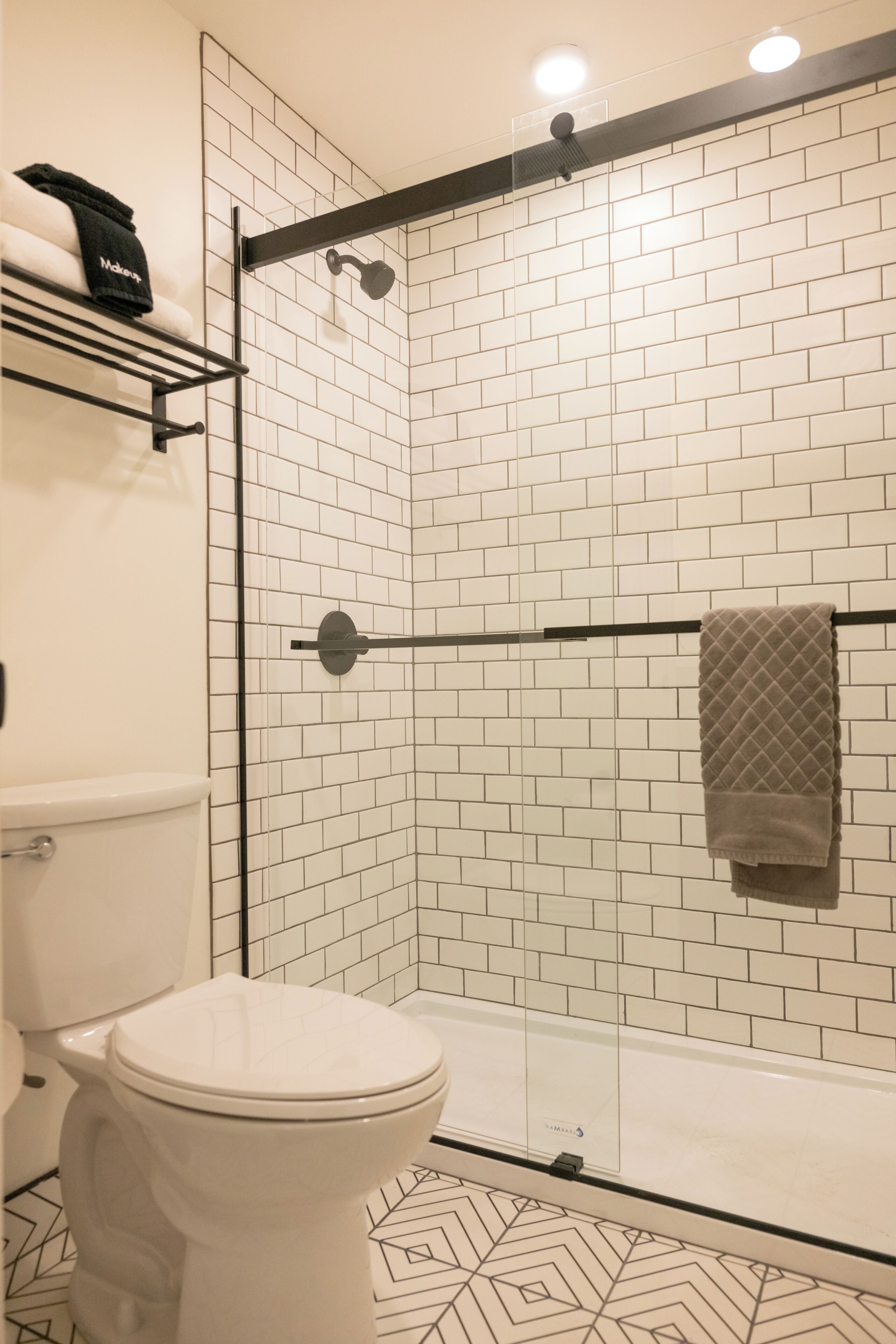 A bathroom with a white toilet, a glass shower enclosure, and a tiled wall.