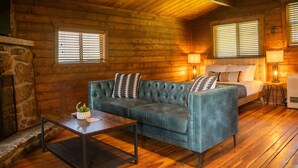 Interior acogedor de una cabaña con techo de madera, un sofá, una cama y una chimenea.