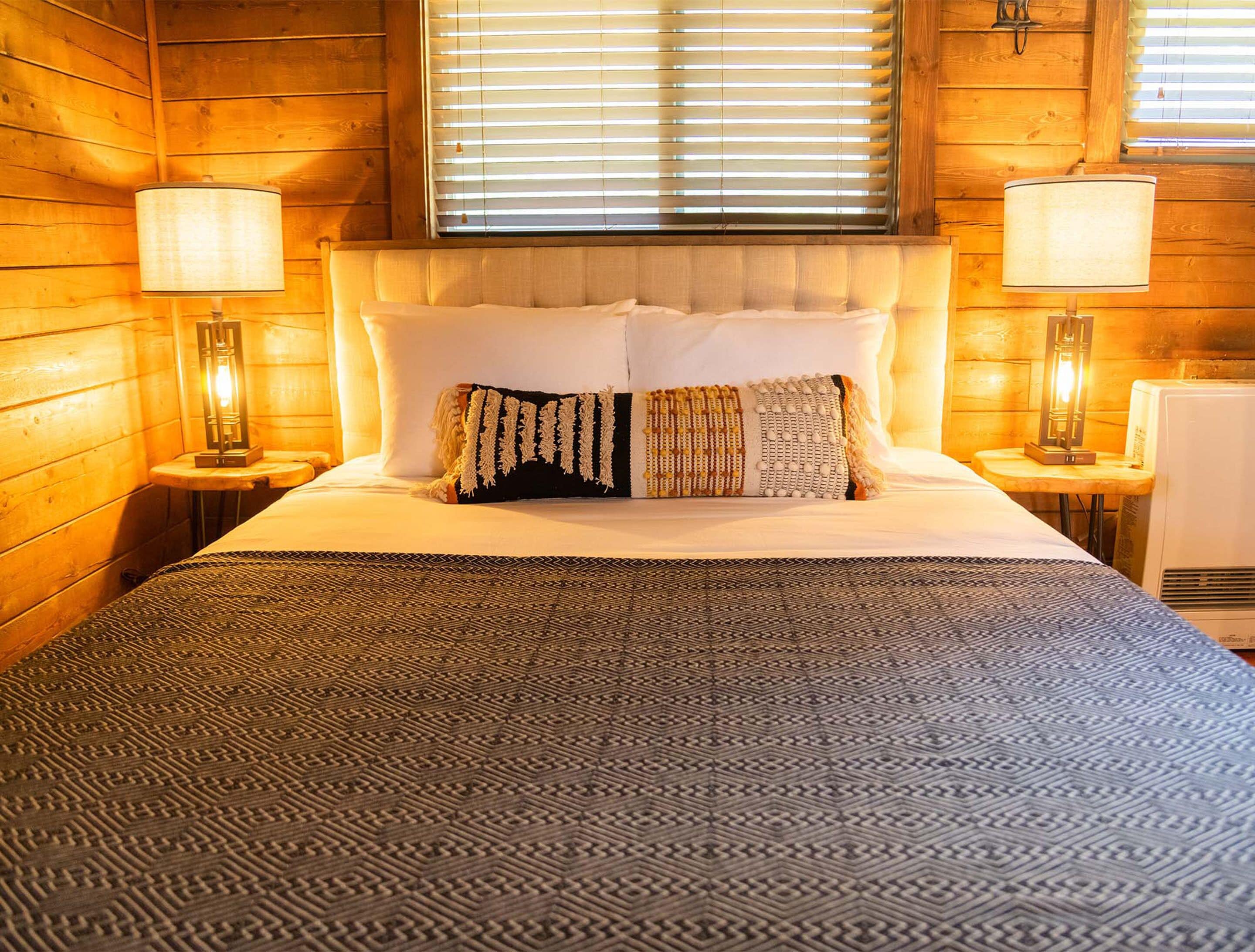 A bed with a patterned bedspread, two white pillows, and a decorative throw.