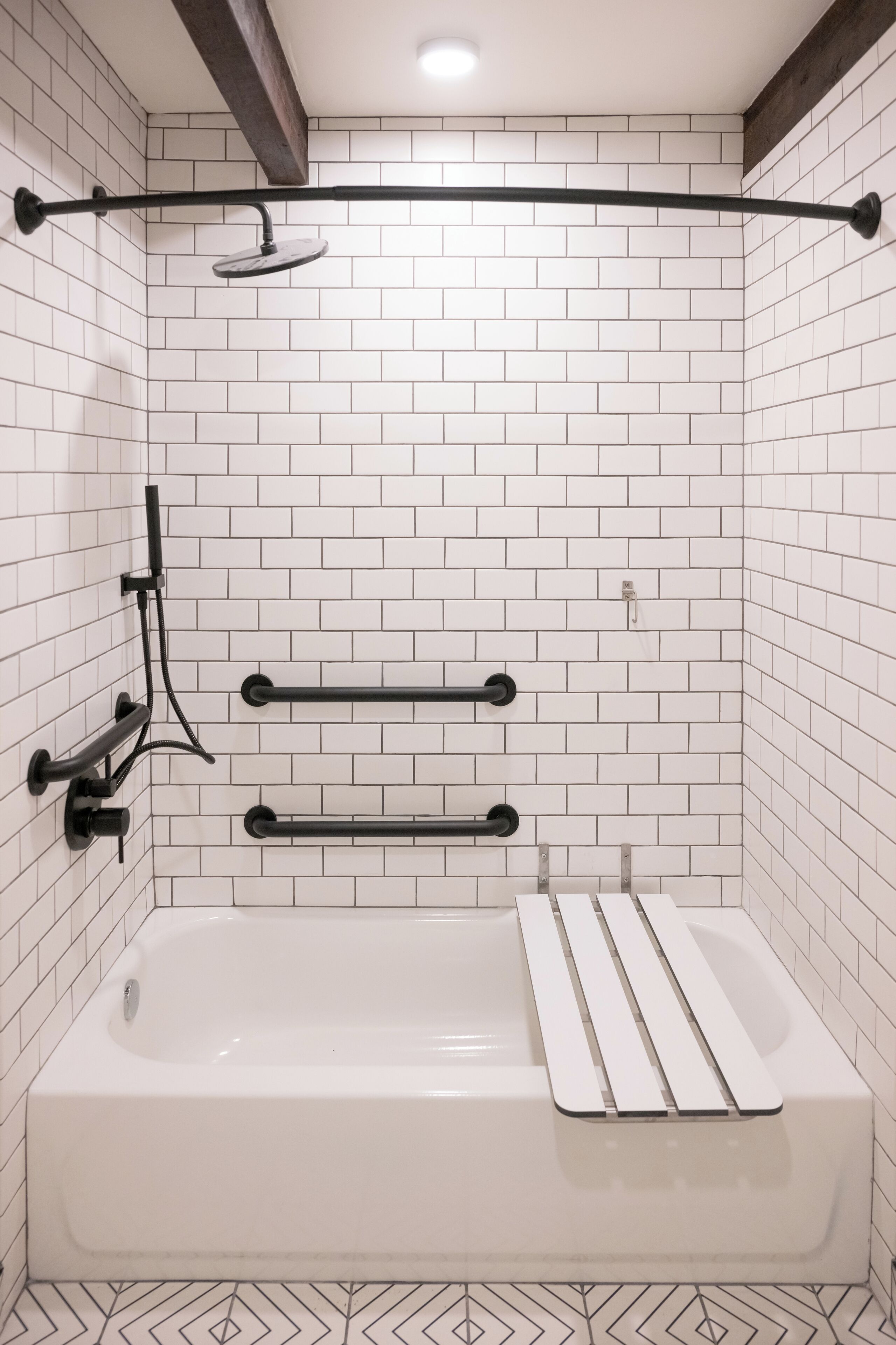 Une salle de bain moderne avec des murs recouverts de carreaux blancs, une baignoire blanche et des accessoires noirs.
