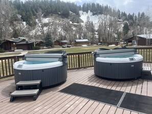 Two hot tubs on a wooden deck with a view of a snowy mountain and houses in the background. - High Creek Lodge & Cabins (Pagosa Springs)