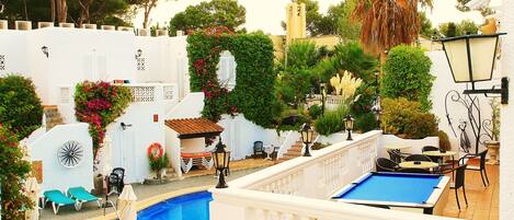 Una piscina al aire libre, sombrillas, sillones reclinables de piscina