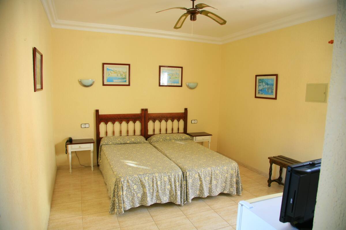 A bedroom with a bed, a nightstand, a television, and a ceiling fan.