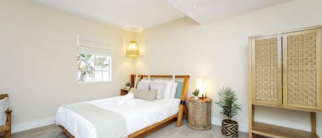 A neatly arranged bedroom with a wooden bed, a bedside lamp, a small potted plant, and a woven cabinet.