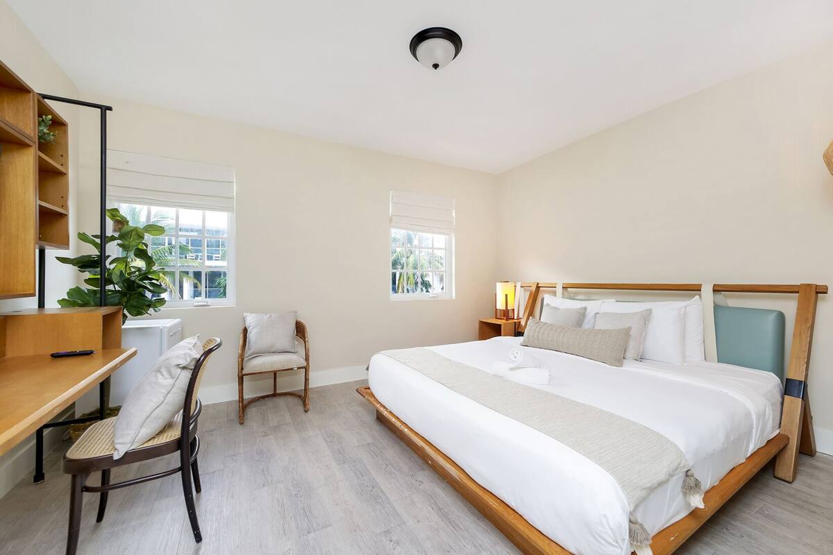A bedroom with a bed, a desk, a chair, and a window.