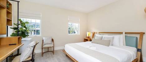 A bedroom with a bed, a desk, a chair, and a window.