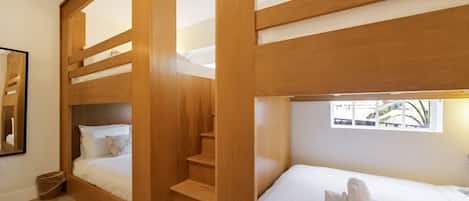 Una habitación pequeña con literas, una pequeña escalera, una cama individual y una ventana con vistas.