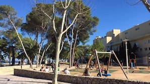 Un parque al aire libre con columpios, muros de piedra y árboles.
