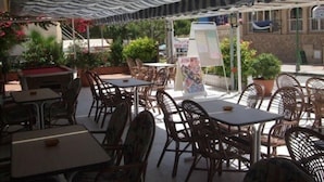 Un patio al aire libre con mesas, sillas, una mesa de billar y plantas en macetas.