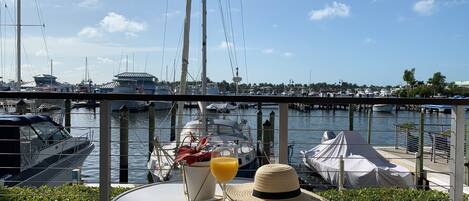A table with a drink and a hat, overlooking a marina with boats.