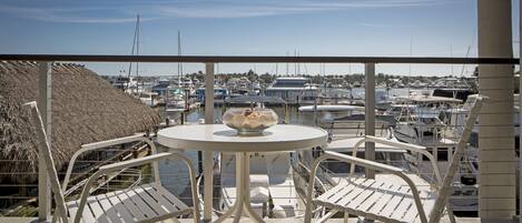 A balcony with a table and chairs overlooking a marina with boats.