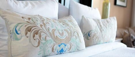 A neatly made bed with white linens and decorative pillows featuring a floral pattern.