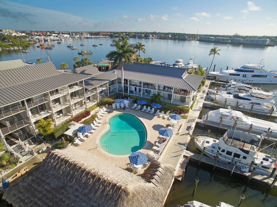 A marina with boats, a swimming pool, and a hotel with multiple floors and balconies.