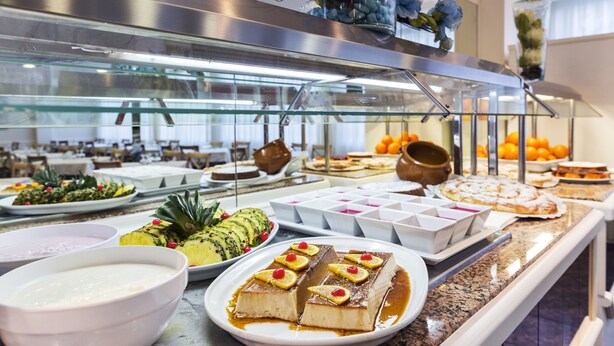 A buffet with various dishes, including a pineapple dish, a dessert with cherries, and several bowls of food.