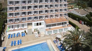 A multi-story hotel with balconies, a swimming pool, and outdoor seating areas.