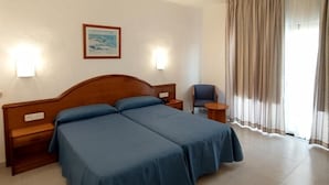 A hotel room with a double bed, two bedside tables, a chair, a painting on the wall, and a window with curtains. - Marina Playa de Palma (Playa de Palma)