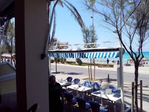 An outdoor seating area with tables and chairs, a covered section, and a view of the beach. - Marina Playa de Palma (Playa de Palma)