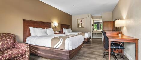 A hotel room with two beds, a desk, a chair, and a sofa.