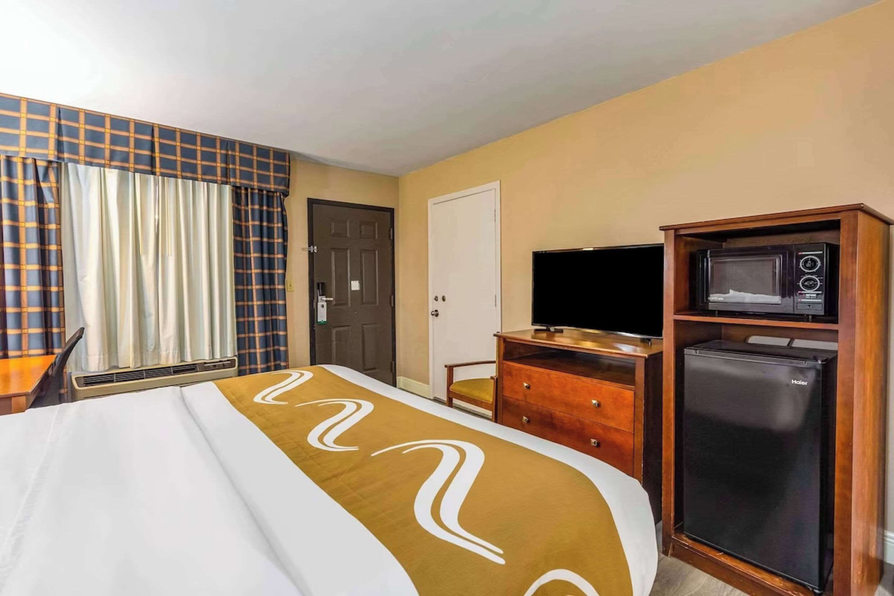 Une chambre d’hôtel équipée d’un lit, d’une télévision, d’un four à micro-ondes et d’un réfrigérateur.